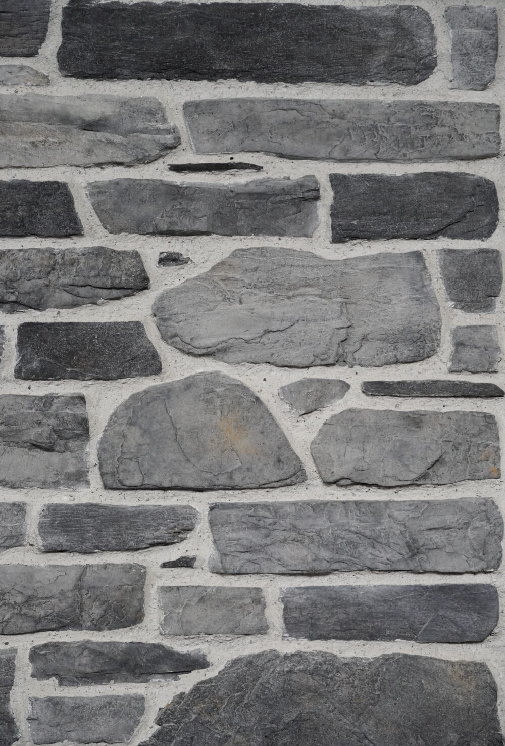 Gray stone masonry wall with rectangular, irregular stones set in light mortar.