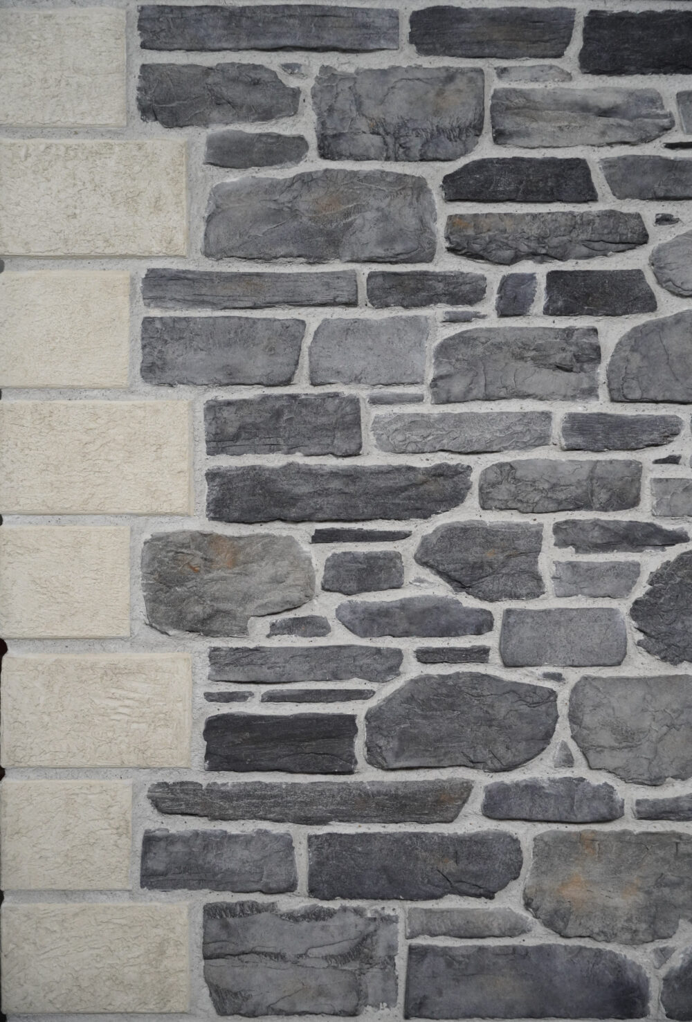 Stone wall pattern with gray cobblestones and vertical beige rectangular blocks along the left edge.