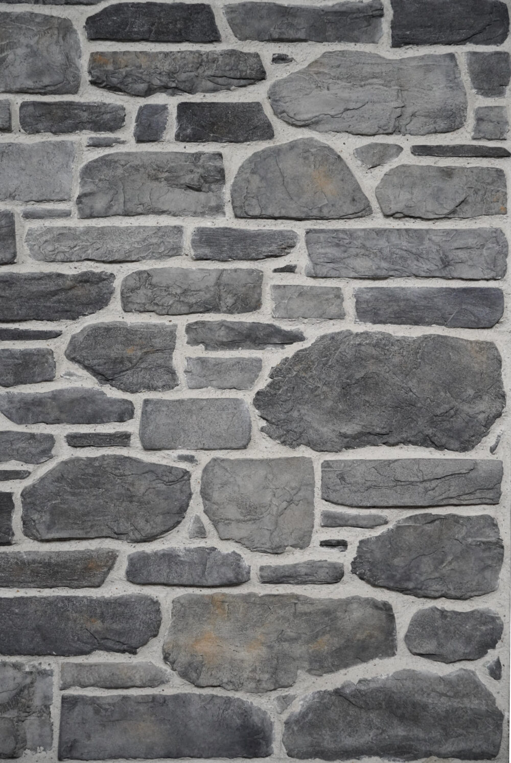 Grey stone wall with irregular rectangular stones and light mortar between them.