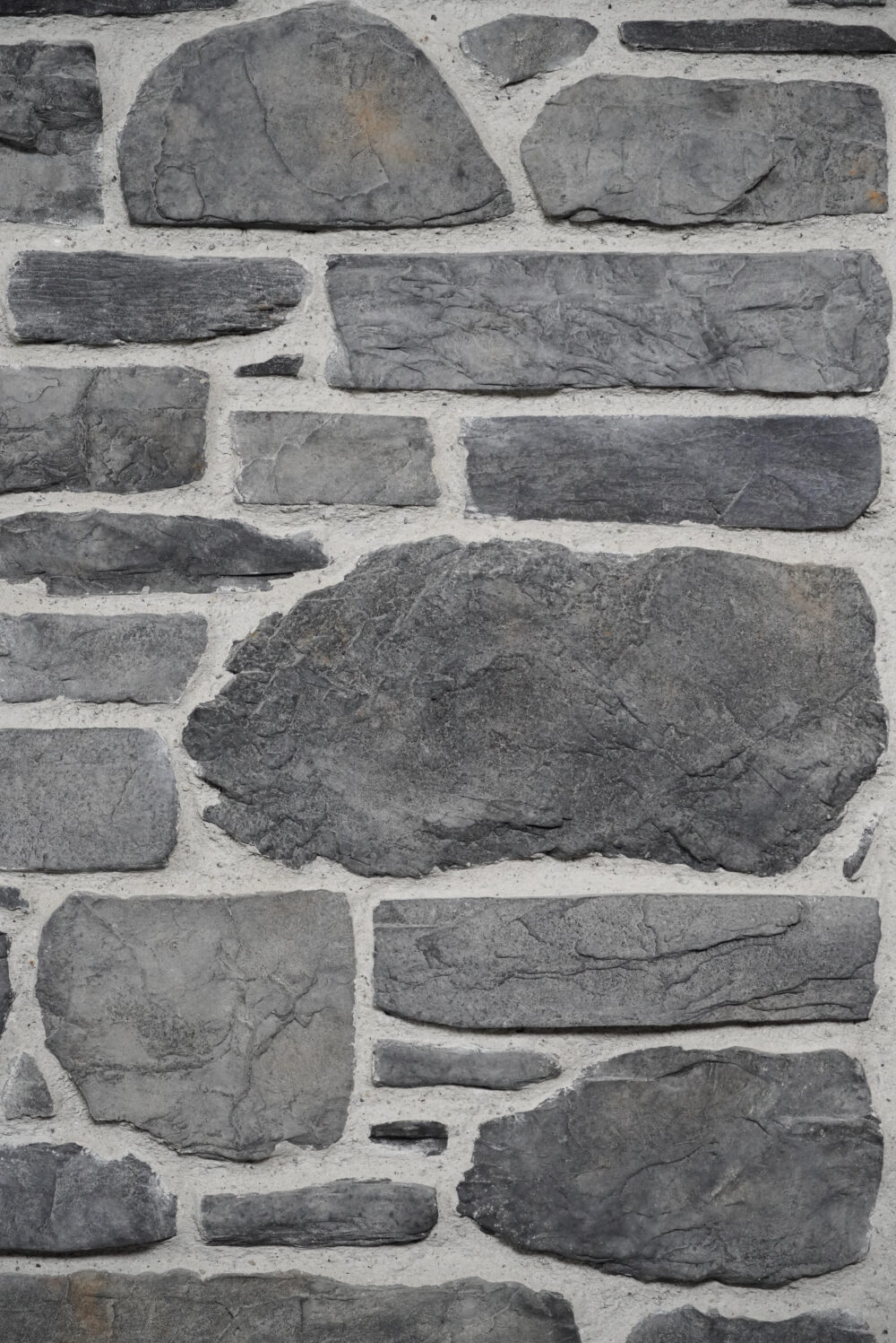 Close-up of a gray stone wall with irregular, stacked stones and light mortar.