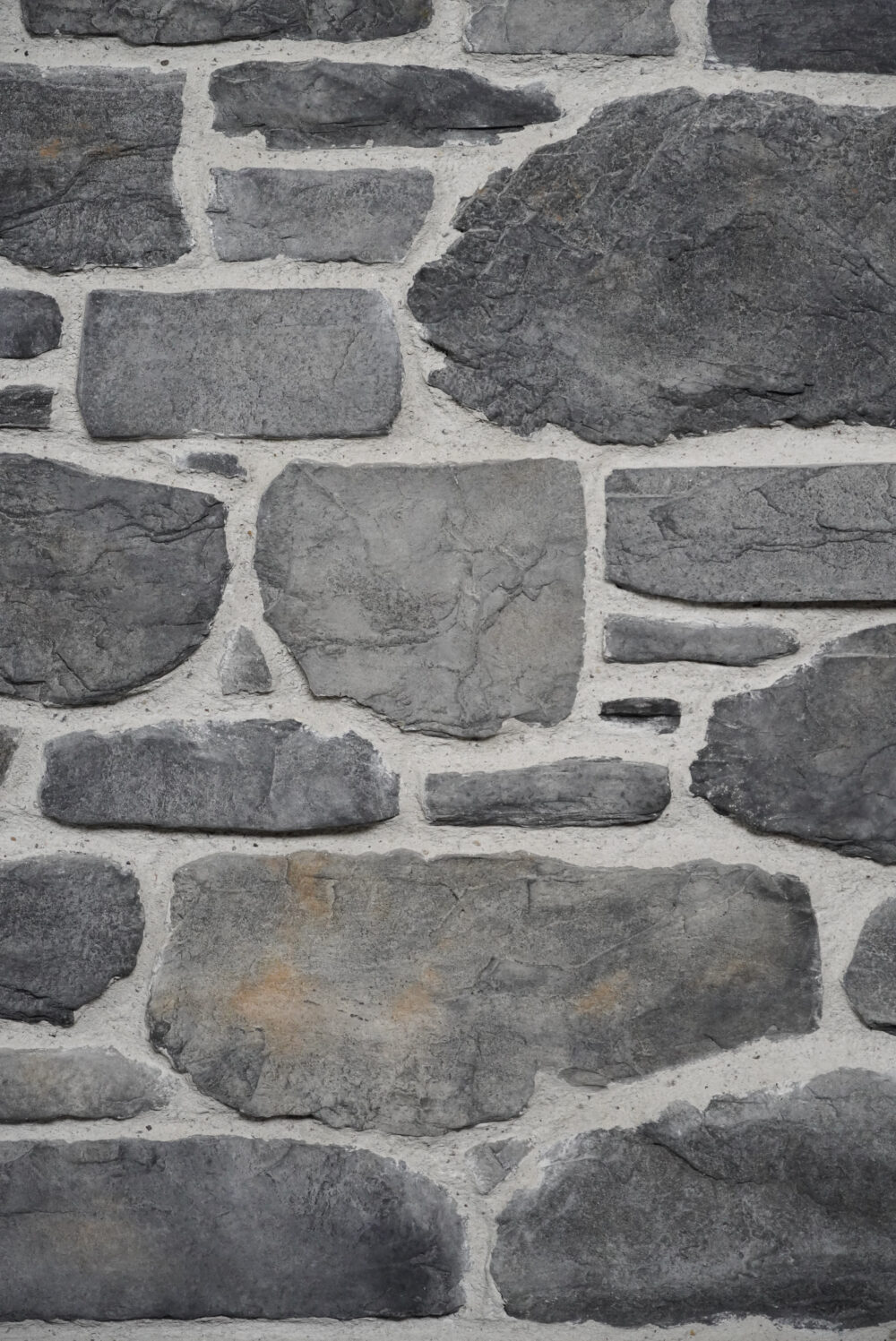 Rough gray stone wall with light gray mortar between irregularly shaped stones.