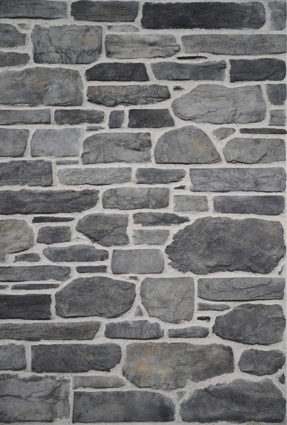 Close-up of a gray stone masonry wall with irregular rectangular stones and light mortar joints