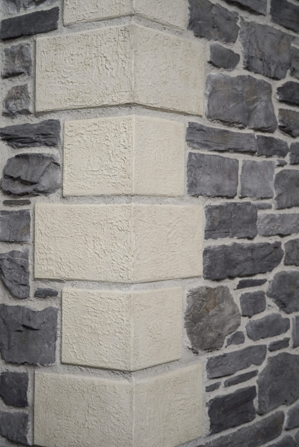 Close-up of a stone wall with light beige rectangular blocks bordered by dark gray stones.