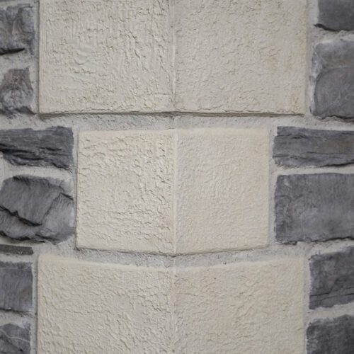Close-up of a beige, rough-textured stone wall with darker gray stones on the sides.