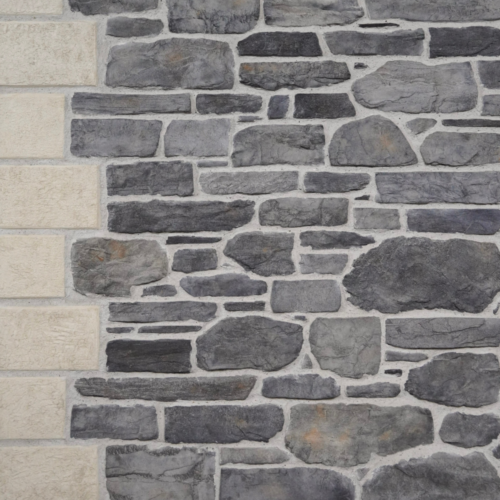 Stone wall made of irregular gray stones with a beige stone column along the left edge.